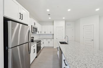 A modern kitchen with white cabinets and a stainless steel refrigerator.